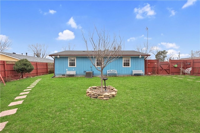 back of house with a lawn, a fenced backyard, and a gate