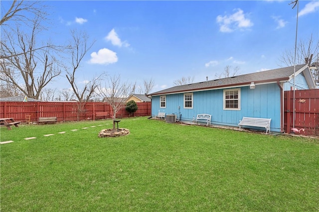 rear view of property with a fenced backyard, central AC, and a yard