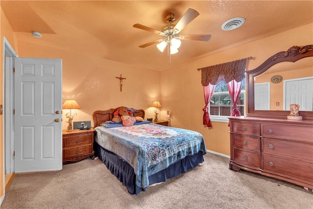 bedroom with visible vents, light colored carpet, a textured ceiling, and ceiling fan