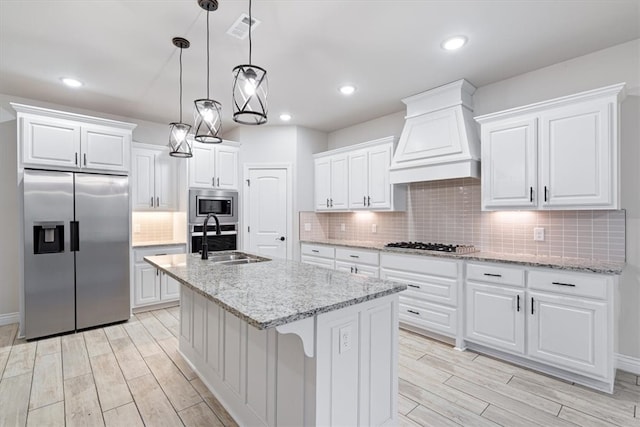 kitchen featuring premium range hood, visible vents, a sink, stainless steel appliances, and wood tiled floor