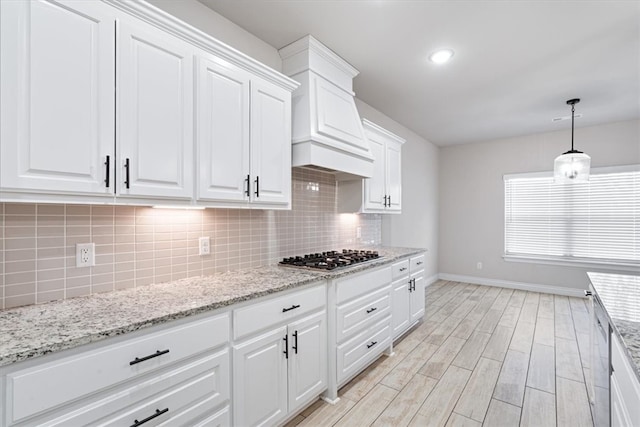 kitchen featuring light wood-type flooring, white cabinetry, stainless steel appliances, decorative backsplash, and baseboards