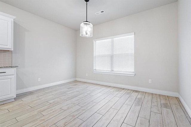 unfurnished dining area featuring visible vents, light wood-type flooring, and baseboards