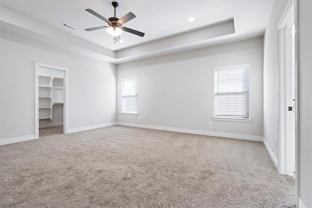 unfurnished bedroom with a tray ceiling, baseboards, carpet, and visible vents