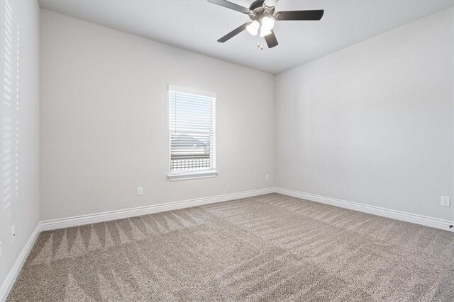 carpeted spare room featuring baseboards and ceiling fan