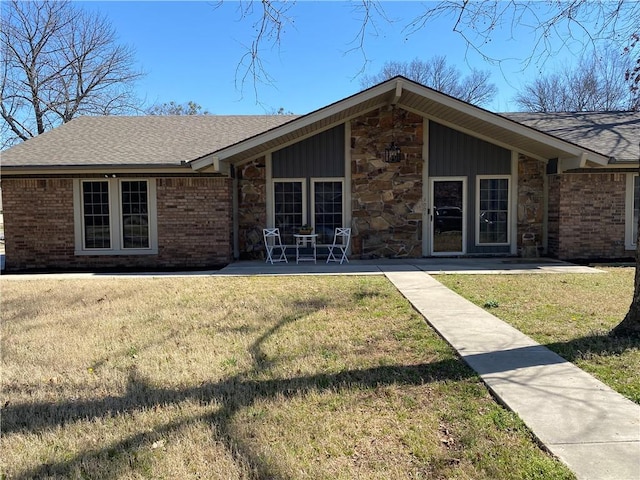 view of front of property featuring a front yard, brick siding, and stone siding