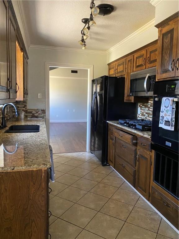 kitchen featuring a sink, black appliances, ornamental molding, and light tile patterned floors