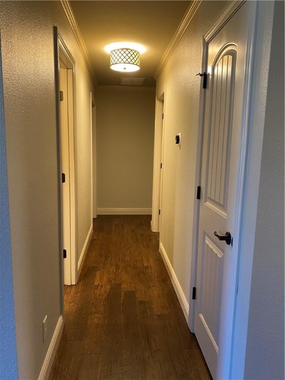 corridor featuring wood finished floors, baseboards, and ornamental molding