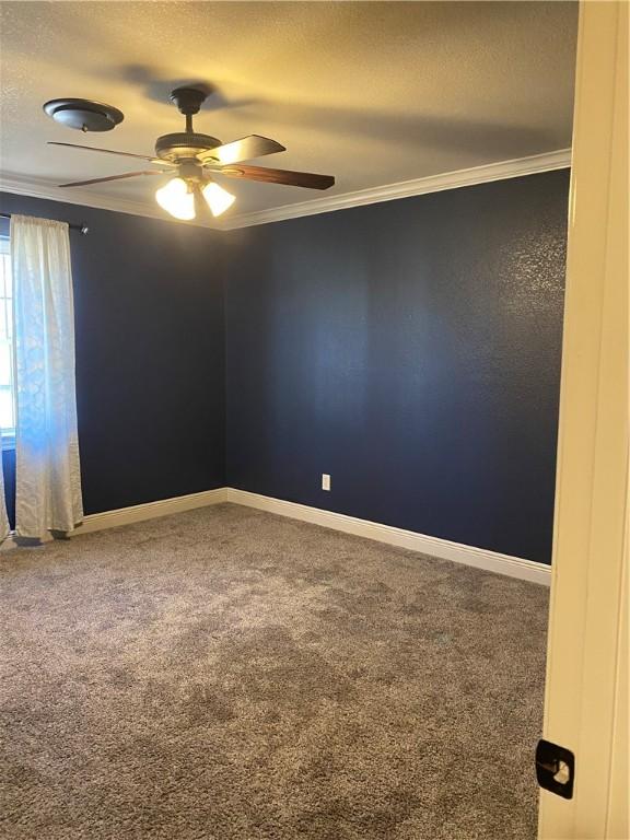 spare room featuring a textured ceiling, carpet, crown molding, baseboards, and ceiling fan