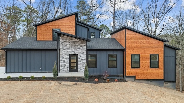 view of front of home featuring board and batten siding, stone siding, roof with shingles, and crawl space