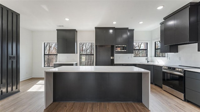 kitchen featuring built in appliances, a center island, light countertops, and decorative backsplash