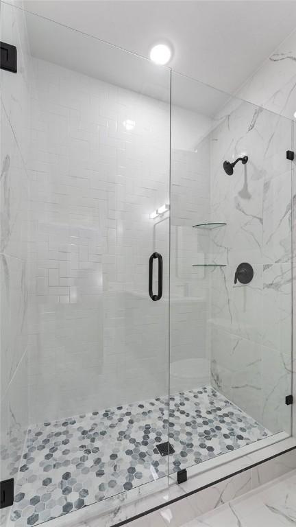 full bathroom with marble finish floor and a stall shower