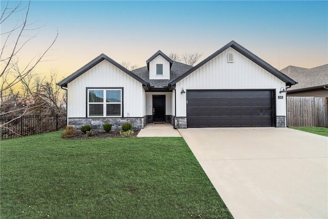 view of front of property featuring a front lawn, driveway, stone siding, fence, and a garage