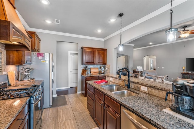 kitchen featuring visible vents, a sink, arched walkways, appliances with stainless steel finishes, and hanging light fixtures