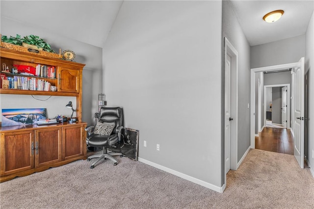 carpeted home office featuring baseboards and lofted ceiling