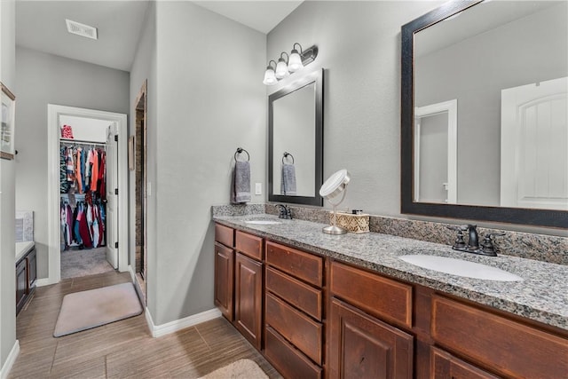 full bathroom featuring a sink, visible vents, a walk in closet, and double vanity