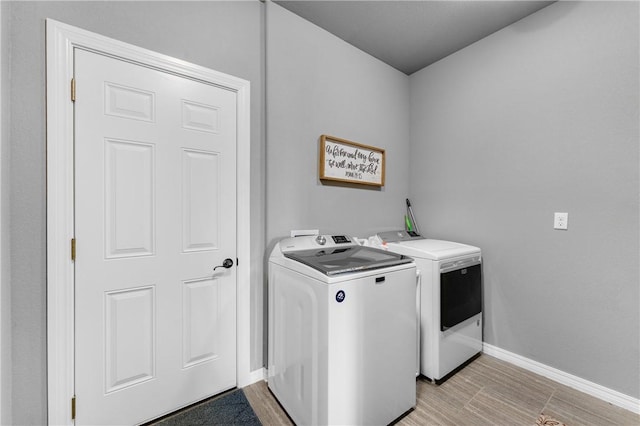 laundry area featuring washer and dryer, laundry area, light wood-style floors, and baseboards