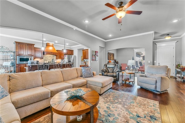 living room featuring crown molding, dark wood-type flooring, recessed lighting, arched walkways, and a ceiling fan