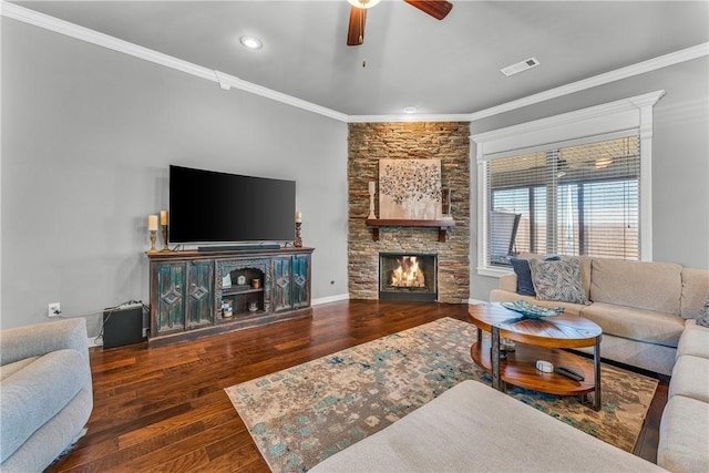 living room with visible vents, ornamental molding, wood finished floors, a stone fireplace, and ceiling fan