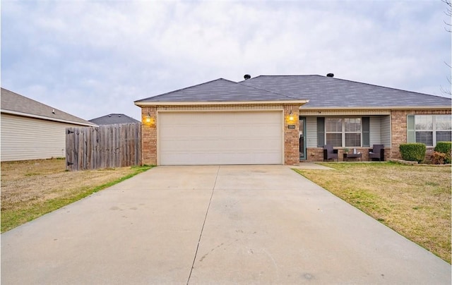 view of front facade with fence, driveway, an attached garage, a front lawn, and brick siding