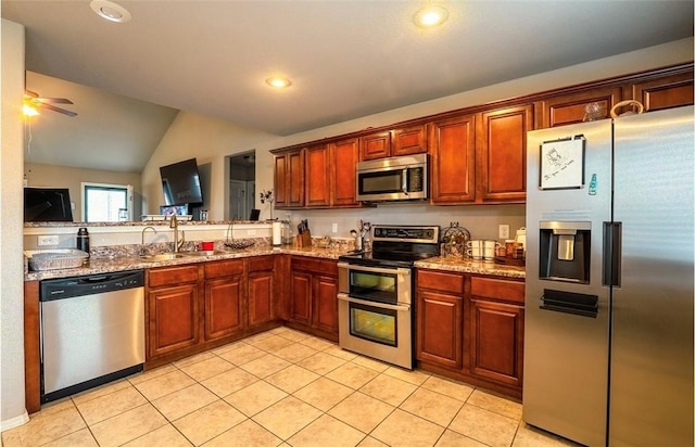 kitchen with vaulted ceiling, light tile patterned floors, appliances with stainless steel finishes, and a sink