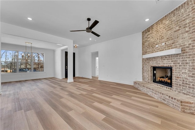 unfurnished living room with baseboards, a brick fireplace, wood finished floors, and a ceiling fan