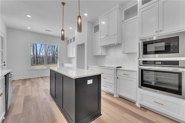 kitchen with light wood-style flooring, backsplash, stainless steel appliances, and light countertops