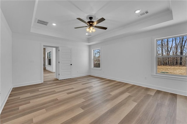 unfurnished room featuring visible vents, light wood-style flooring, crown molding, and a raised ceiling