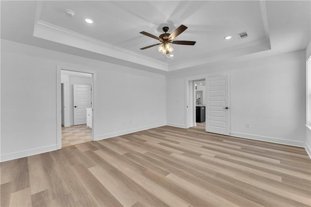 spare room with a tray ceiling, ornamental molding, visible vents, and ceiling fan