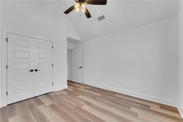 unfurnished bedroom featuring visible vents, high vaulted ceiling, a closet, light wood finished floors, and baseboards