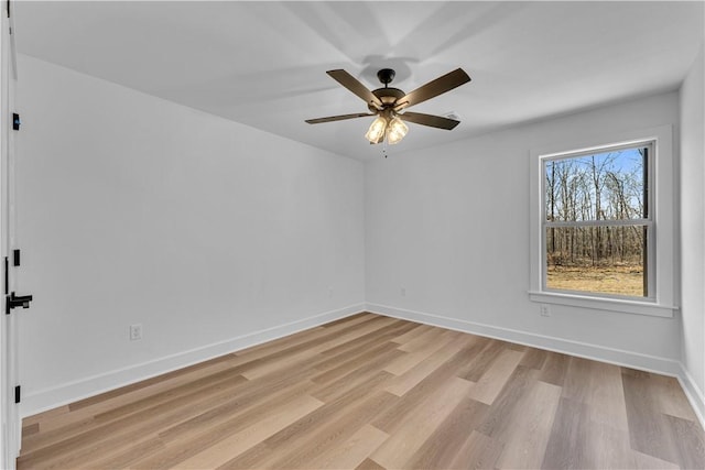 spare room with baseboards, light wood-style floors, and a ceiling fan