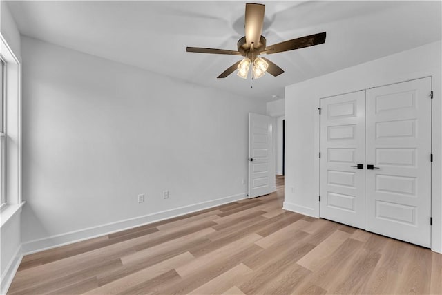 unfurnished bedroom with light wood-style flooring, baseboards, a closet, and ceiling fan