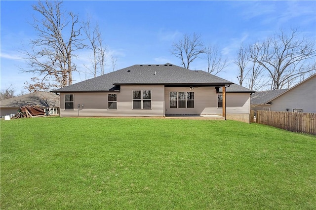 back of house featuring a lawn, roof with shingles, a patio, and fence