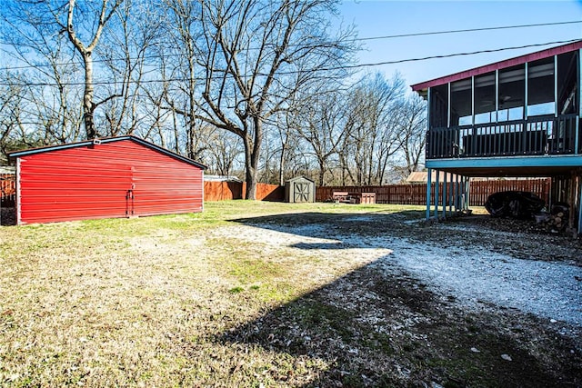 view of yard featuring an outbuilding, a sunroom, fence, and a shed