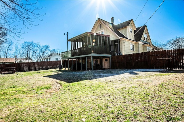 back of house with a fenced backyard, a lawn, a sunroom, and a chimney