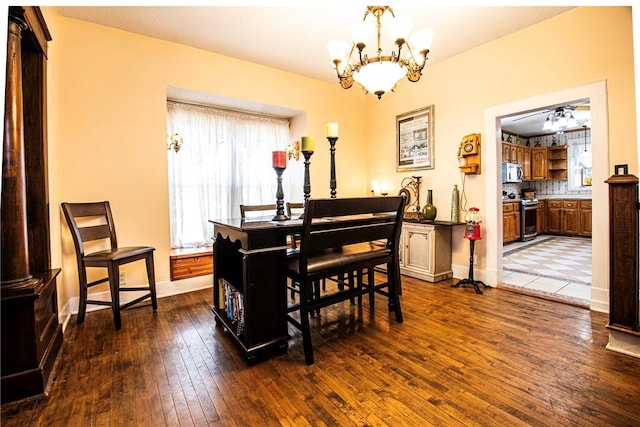 dining space featuring dark wood-type flooring, baseboards, and a chandelier