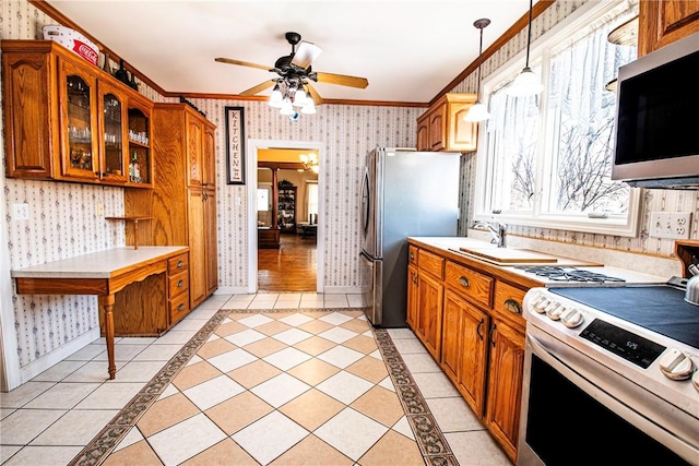 kitchen with wallpapered walls, ornamental molding, stainless steel appliances, glass insert cabinets, and brown cabinets