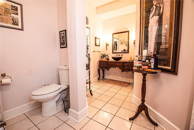 half bathroom featuring tile patterned flooring, toilet, vanity, and baseboards