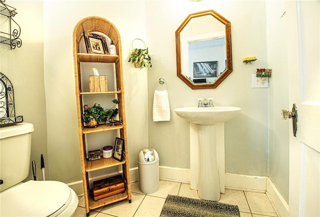 half bathroom with tile patterned flooring, toilet, and baseboards