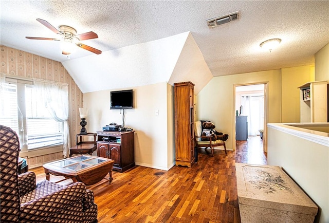 living room with a ceiling fan, visible vents, vaulted ceiling, wood-type flooring, and a textured ceiling