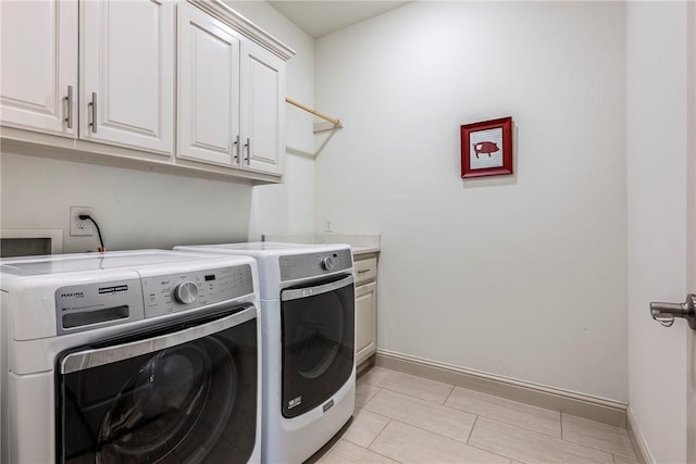 washroom featuring cabinet space, baseboards, and washer and clothes dryer