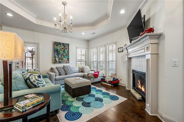 living room featuring a wealth of natural light, a raised ceiling, dark wood-style flooring, and a fireplace