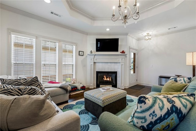 living area featuring visible vents, crown molding, a raised ceiling, and wood finished floors