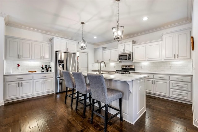 kitchen with light countertops, a breakfast bar area, dark wood-style flooring, and appliances with stainless steel finishes