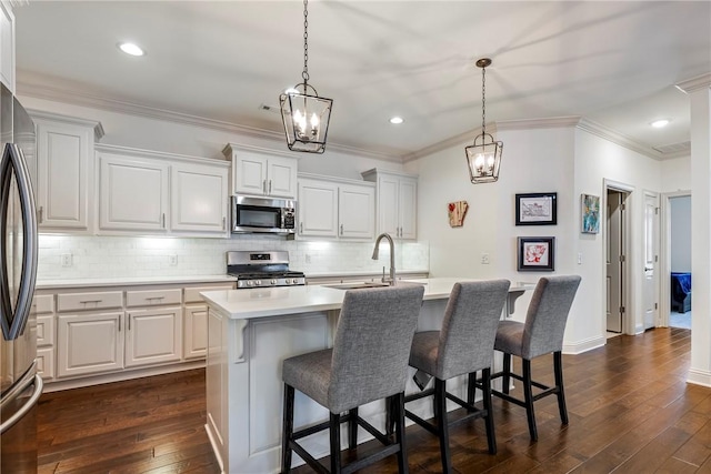 kitchen featuring dark wood-style floors, an island with sink, a sink, stainless steel appliances, and light countertops