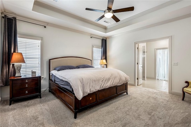 bedroom with a tray ceiling, light colored carpet, and ornamental molding