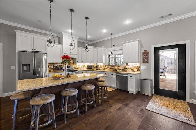 kitchen featuring visible vents, a center island, crown molding, stainless steel appliances, and dark wood-style flooring