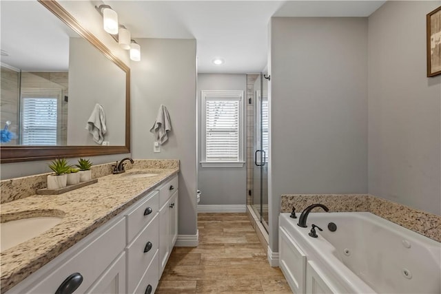 bathroom with baseboards, double vanity, a stall shower, a tub with jets, and a sink