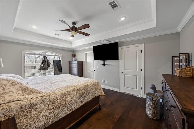 bedroom with a tray ceiling, visible vents, dark wood-style flooring, and ornamental molding