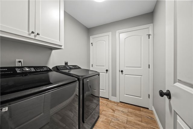 laundry area featuring cabinet space, washing machine and dryer, light wood finished floors, and baseboards