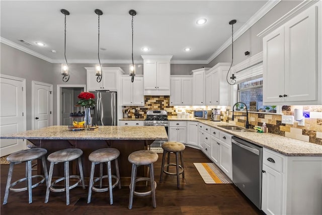 kitchen with a sink, a kitchen island, stainless steel appliances, white cabinets, and dark wood-style flooring